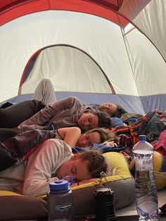 two women are sleeping in a tent with water bottles on the floor next to them