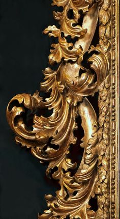 an ornate gold framed mirror on a black wall