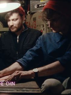 two men sitting at a table working on a laptop computer with the caption, what's the chin?