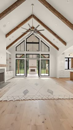 an open living room with wood floors and white walls, ceiling fan and large windows