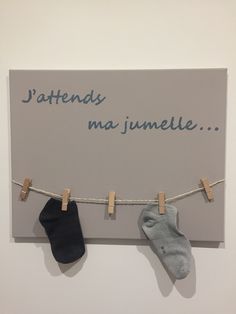 two pairs of socks hanging from clothesline with words written on the wall behind them