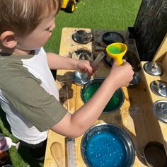 a little boy that is standing in front of a table with some bowls and spoons