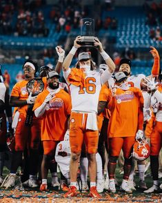 the football players are all wearing orange and white uniforms with their hands in the air