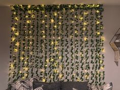 a living room with a couch and green plants on the wall above it, along with hanging lights