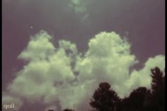 an airplane is flying in the sky with some clouds behind it and trees on the other side