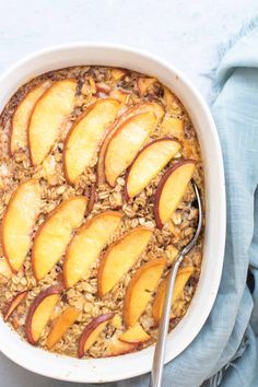 a bowl filled with oatmeal topped with sliced peaches next to a spoon