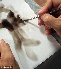 a person is painting on paper with a brush