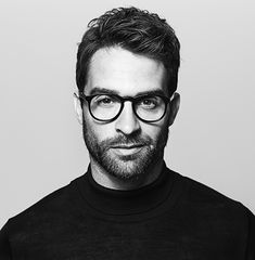 a black and white photo of a man with glasses looking at the camera in a circle