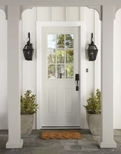 a white front door with two planters on either side