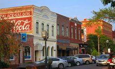 several cars are parked on the street in front of buildings with coca - cola signs