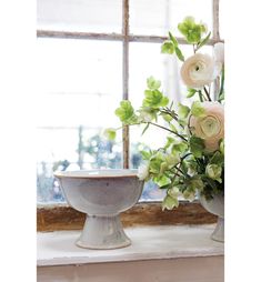 a vase filled with flowers sitting on top of a window sill next to a bowl