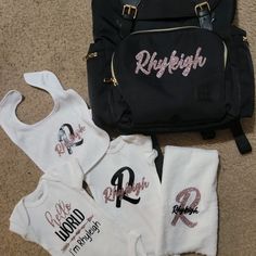 three personalized onesuits and a backpack on the floor