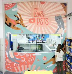 a woman standing in front of a colorful wall with lots of cats and dogs on it