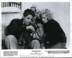 an old black and white photo of two people sitting on a couch looking at a cell phone