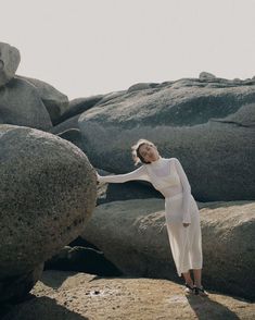 a woman standing on top of a large rock next to a pile of rocks and boulders