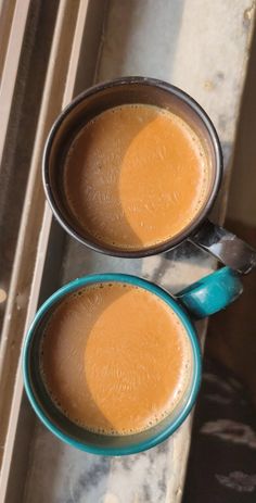 two cups filled with liquid sitting on top of a counter next to an open window