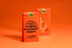 two orange bags with food on them sitting next to each other in front of an orange background