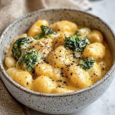 a white bowl filled with macaroni and cheese covered in broccoli florets