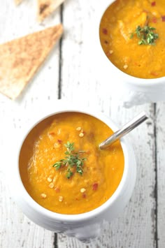 two white bowls filled with soup on top of a wooden table