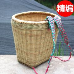 a woven basket sitting on top of a cement wall next to a blue and pink rope