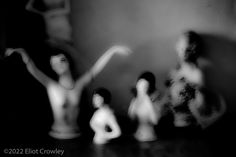 black and white photograph of figurines on table with woman's body in motion