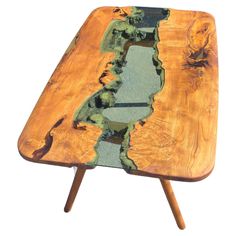 a wooden table with green and blue paint on it's surface, in the shape of a river