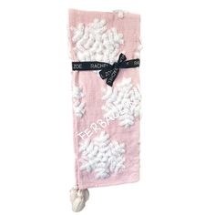 a pink towel with white flowers on it and a black ribbon hanging from the side