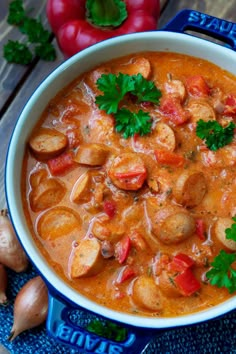 a bowl of soup with potatoes, carrots and parsley in it on a wooden table