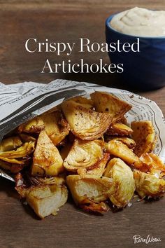 crispy roasted artichokes on a plate next to a bowl of dip