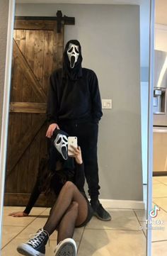 a person wearing a mask and sitting on the floor in front of a mirror with their legs crossed