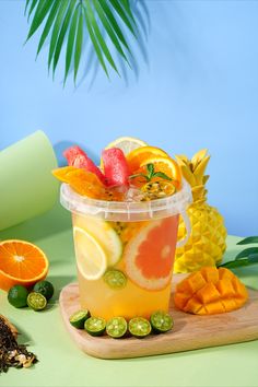 a cup filled with fruit sitting on top of a wooden cutting board next to sliced oranges