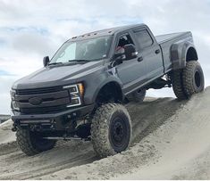 a gray truck driving on top of a sandy hill