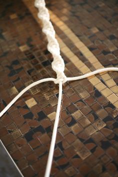 a close up of a white cord on a tiled floor with brown and black tiles