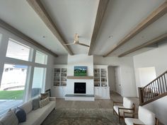 a living room with white walls and wood beams