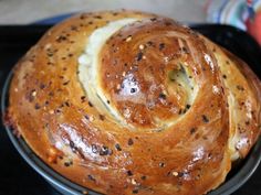 a loaf of bread sitting on top of a black pan covered in butter and poppy seeds