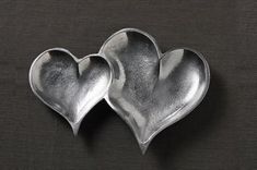 two metal heart shaped dishes sitting on top of a table