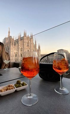 two wine glasses sitting on top of a table next to plates and bowls of food