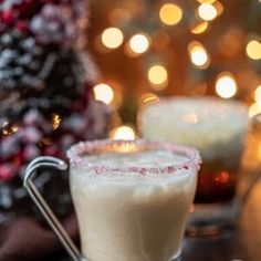 two glasses filled with liquid sitting on top of a table next to a christmas tree