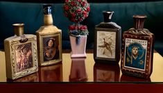 four different types of perfume bottles sitting on a table next to a vase with flowers in it