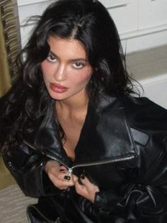 a woman in black leather jacket sitting on the floor