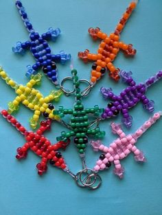 six different colored beads are arranged in the shape of cross - stitched figures on a blue surface