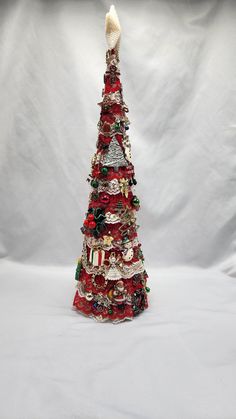 a small christmas tree with ornaments on it's sides and a white background behind it