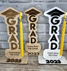 three wooden signs with graduation caps and tassels on them, one that says grad