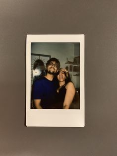 two people are taking a selfie in front of a gray wall with a black and white photo