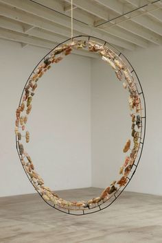 a large circular sculpture hanging from the ceiling in an empty room with white walls and concrete flooring