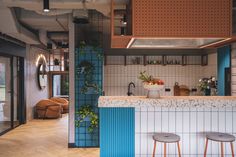 a kitchen with blue and white tiles on the walls, two stools at the bar