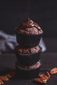 three chocolate cupcakes stacked on top of each other and drizzled with chocolate