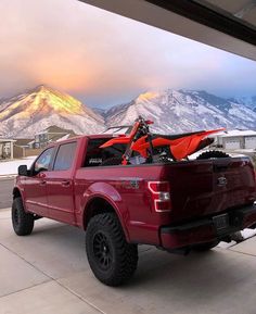 a red truck parked in front of a mountain