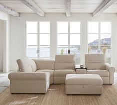 a living room with white furniture and large windows overlooking the water in front of it