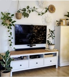 a flat screen tv sitting on top of a wooden table next to a white cabinet